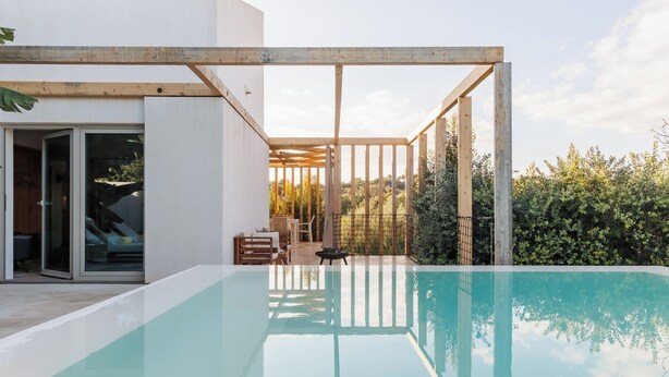 A modern outdoor pool area with a clear view of the surrounding landscape, wooden pergola, and a glass door leading to a patio. - Laranjal Farm House (Olhao)