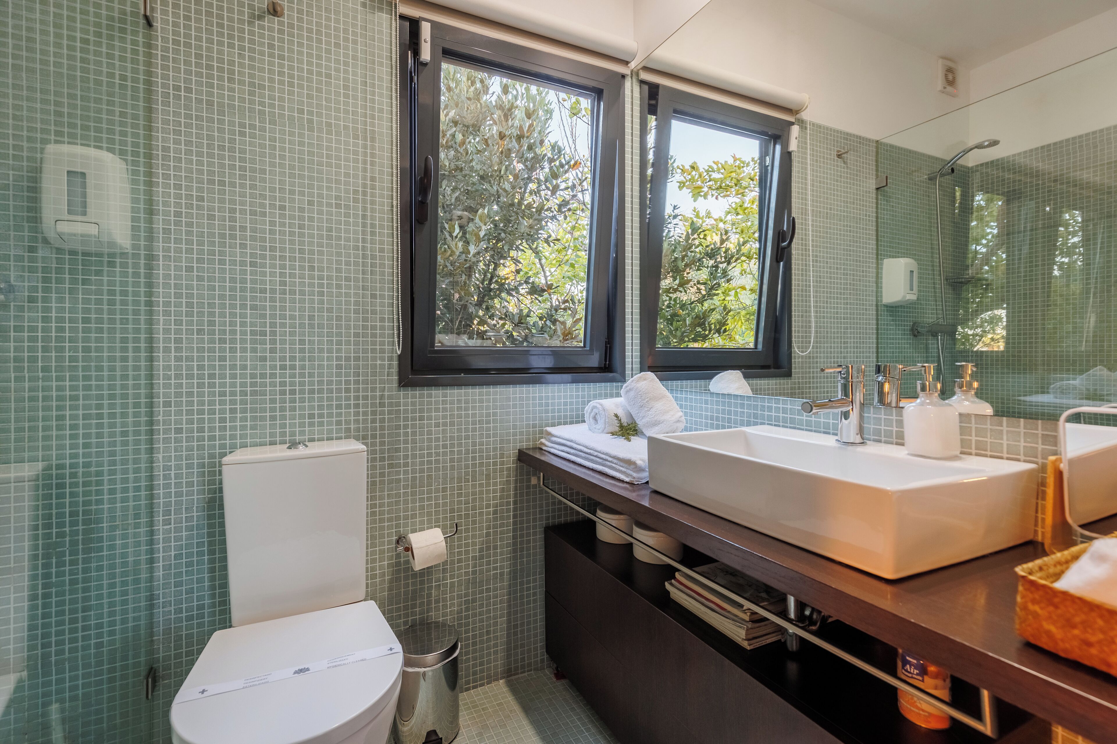 Un baño con inodoro, bidé y dos lavamanos con espejos.