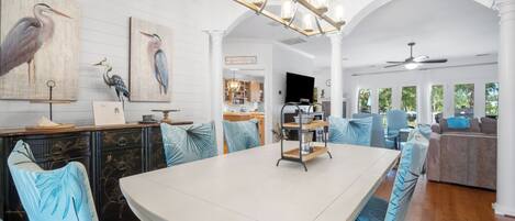 A spacious dining area with a large table, blue patterned chairs, and a chandelier.