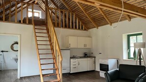 Un dormitorio tipo loft con escalera de madera, kitchenette y comedor.