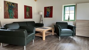 Una sala de estar moderna con un sofá, dos sillones, una mesa de centro y tres cuadros en la pared.