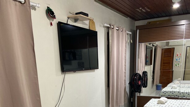 Une chambre d’hôtel avec un lit, un téléviseur fixé au mur, un sèche-cheveux et un miroir qui reflète la pièce.