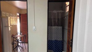 Une pièce comprenant un coin repas, une salle de bain avec des carreaux décoratifs et un climatiseur blanc fixé au mur.