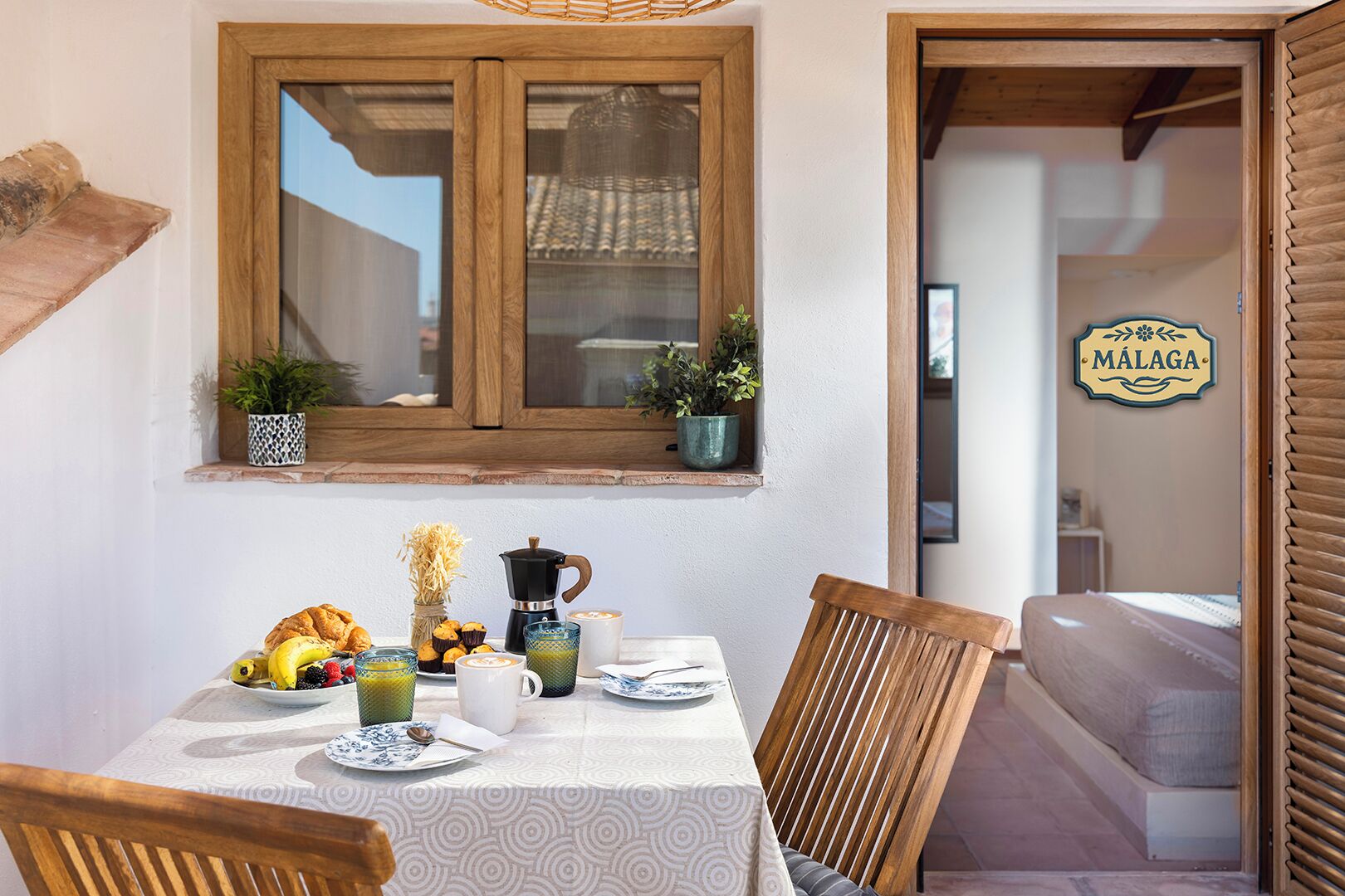 A dining area with a table set for breakfast, including pastries, fruits, and coffee.