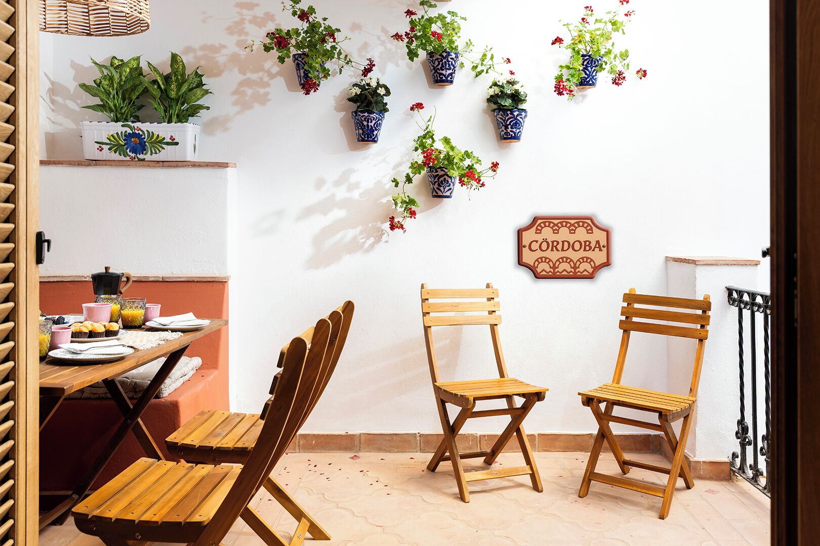 A cozy dining area with wooden chairs, a table set for breakfast, and potted plants on the wall.