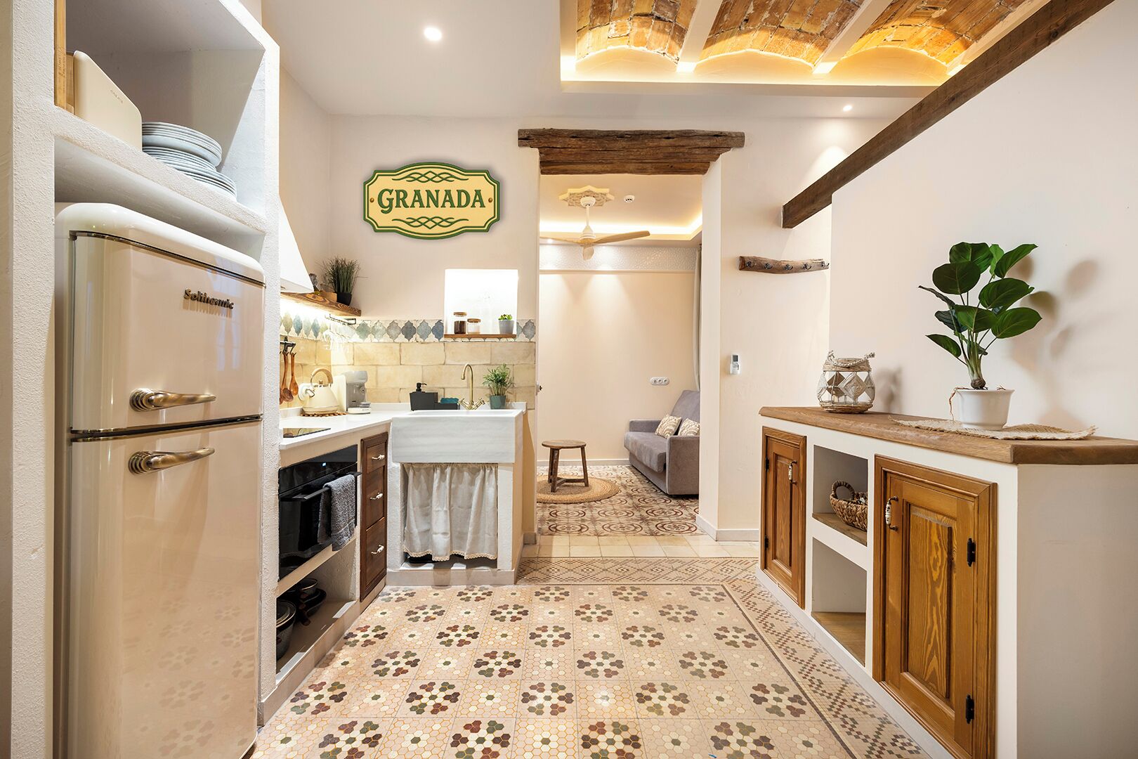 A kitchen with a vintage refrigerator, a sign reading 'GRANADA', and a patterned floor.