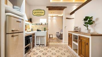 A kitchen with a vintage refrigerator, a sign reading 'GRANADA', and a patterned floor.