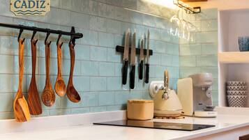 Una cocina con utensilios de madera colgados en un perchero, una cafetera y un tostador sobre la encimera.
