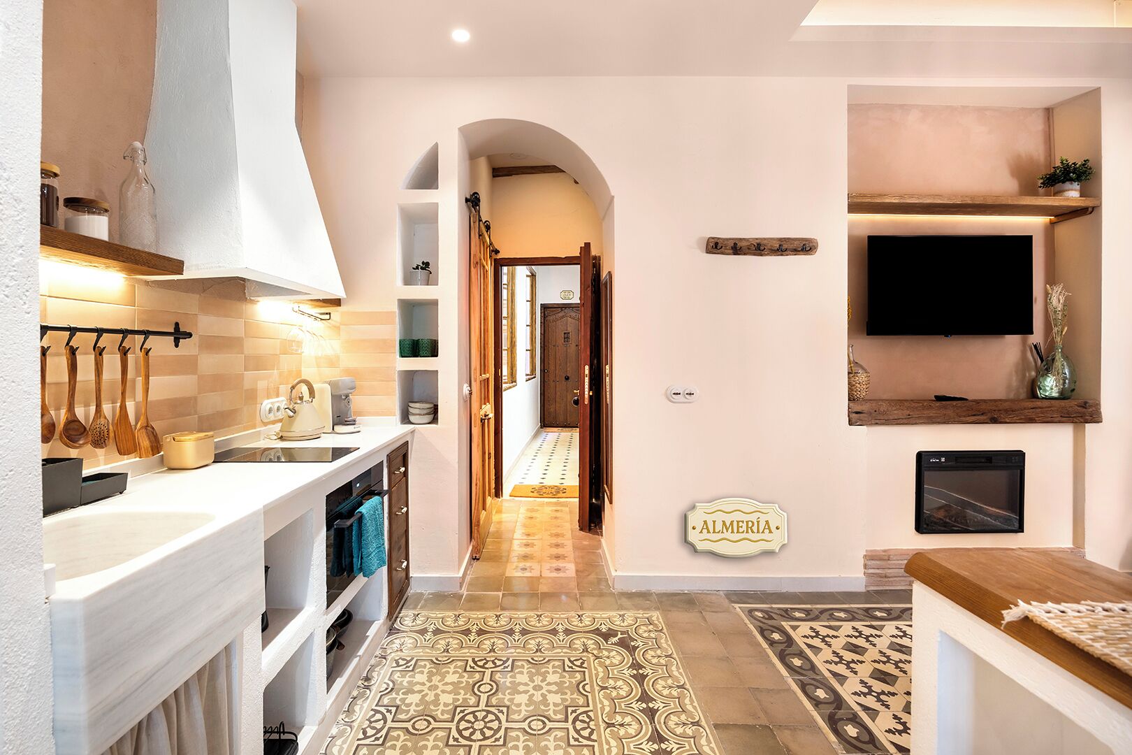 Una cocina moderna con una isla central, horno empotrado y televisor montado sobre el horno.