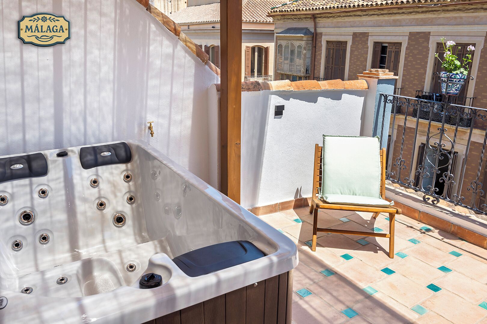 A spa area with a hot tub and a chair on a balcony with a tiled floor and a railing.