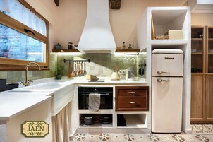 A compact kitchen with a built-in oven, a refrigerator, and a window with a view of the outdoors.