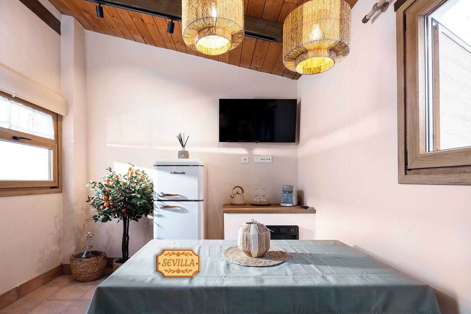 A room with a table, a refrigerator, a television, and a window.