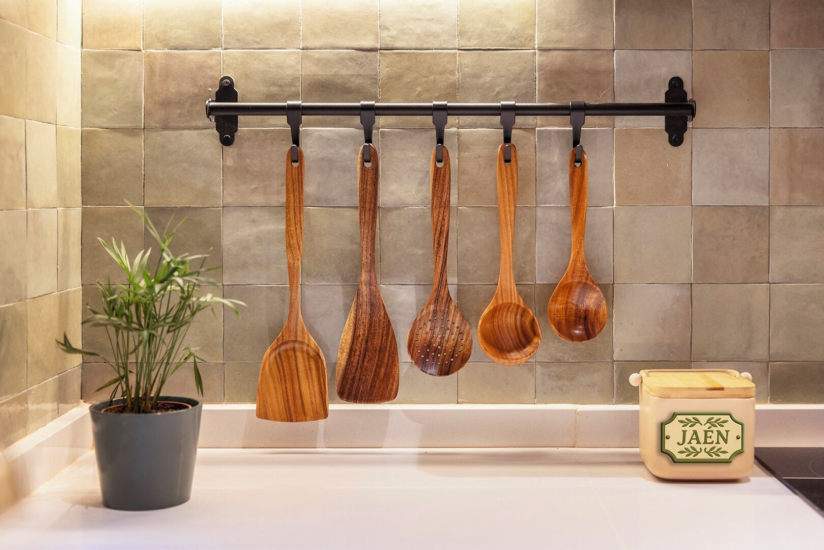 A kitchen with a wooden spoon rack, a potted plant, and a jar labeled "JAEN".