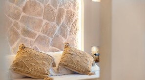 A bed with two textured pillows and a stone wall behind it. - Mi Andalusia Hotel Experience (Málaga)