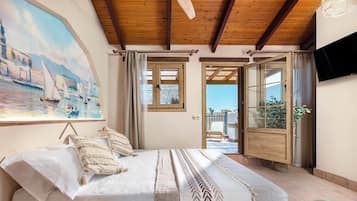 Ein Schlafzimmer mit Bett, einem Gemälde und Blick ins Freie.
