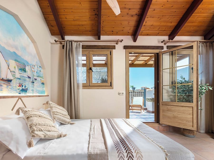 Un dormitorio con cama, un cuadro y vistas al exterior.