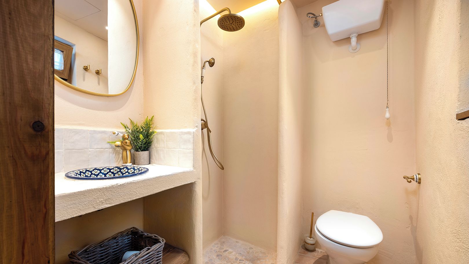 A compact bathroom with a shower, toilet, and a small sink area with decorative tiles.