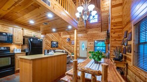 L’intérieur d’une cabane en rondins comprend une cuisine, un coin repas et un escalier menant à une mezzanine.
