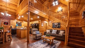 Un intérieur spacieux de chalet en bois, comprenant un espace de vie central, une cuisine et un coin repas.