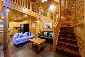 A wooden interior with a staircase, a sofa, a coffee table, and a kitchen area.