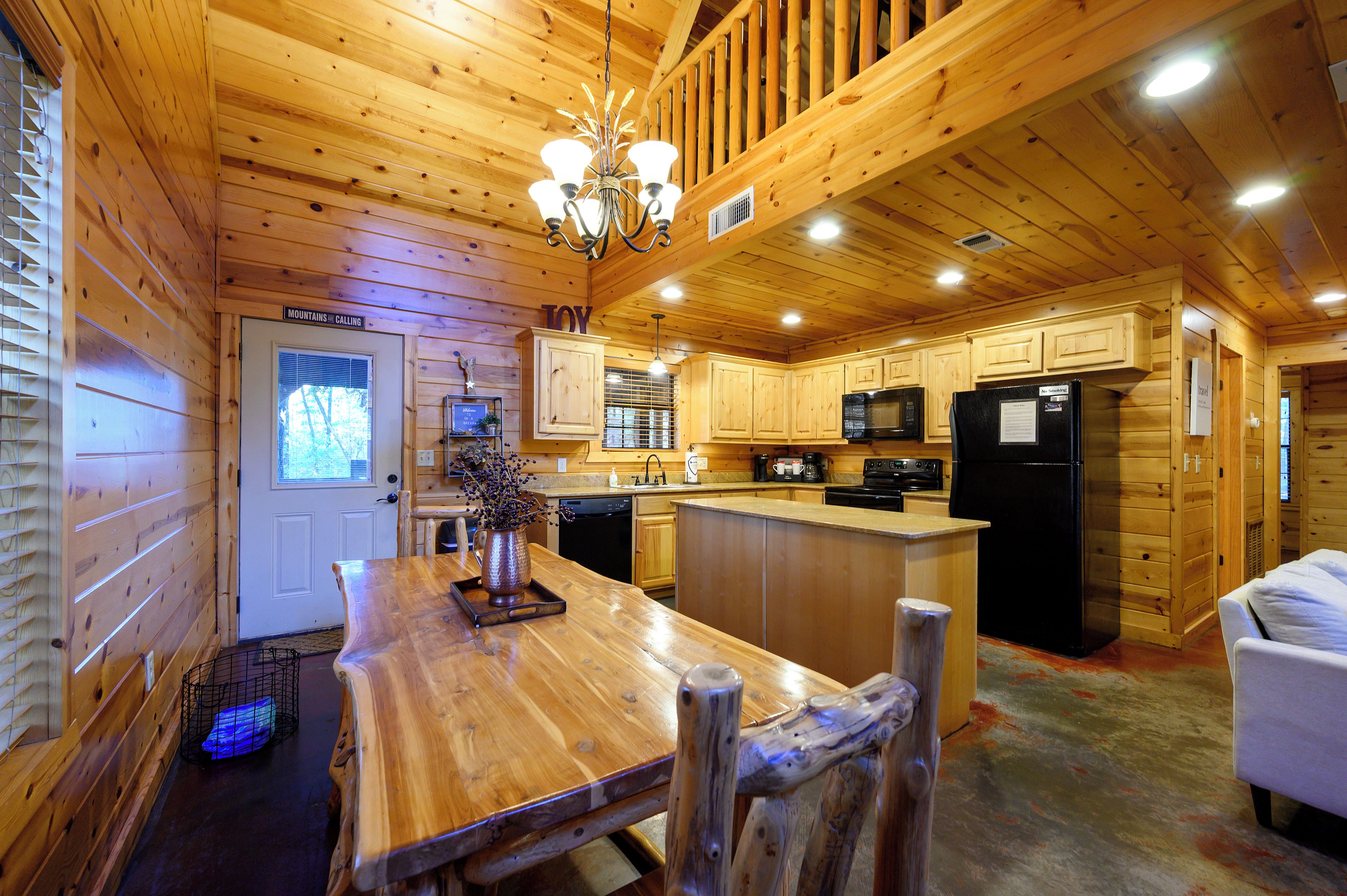 A wooden cabin interior with a kitchen, dining area, and a living space.