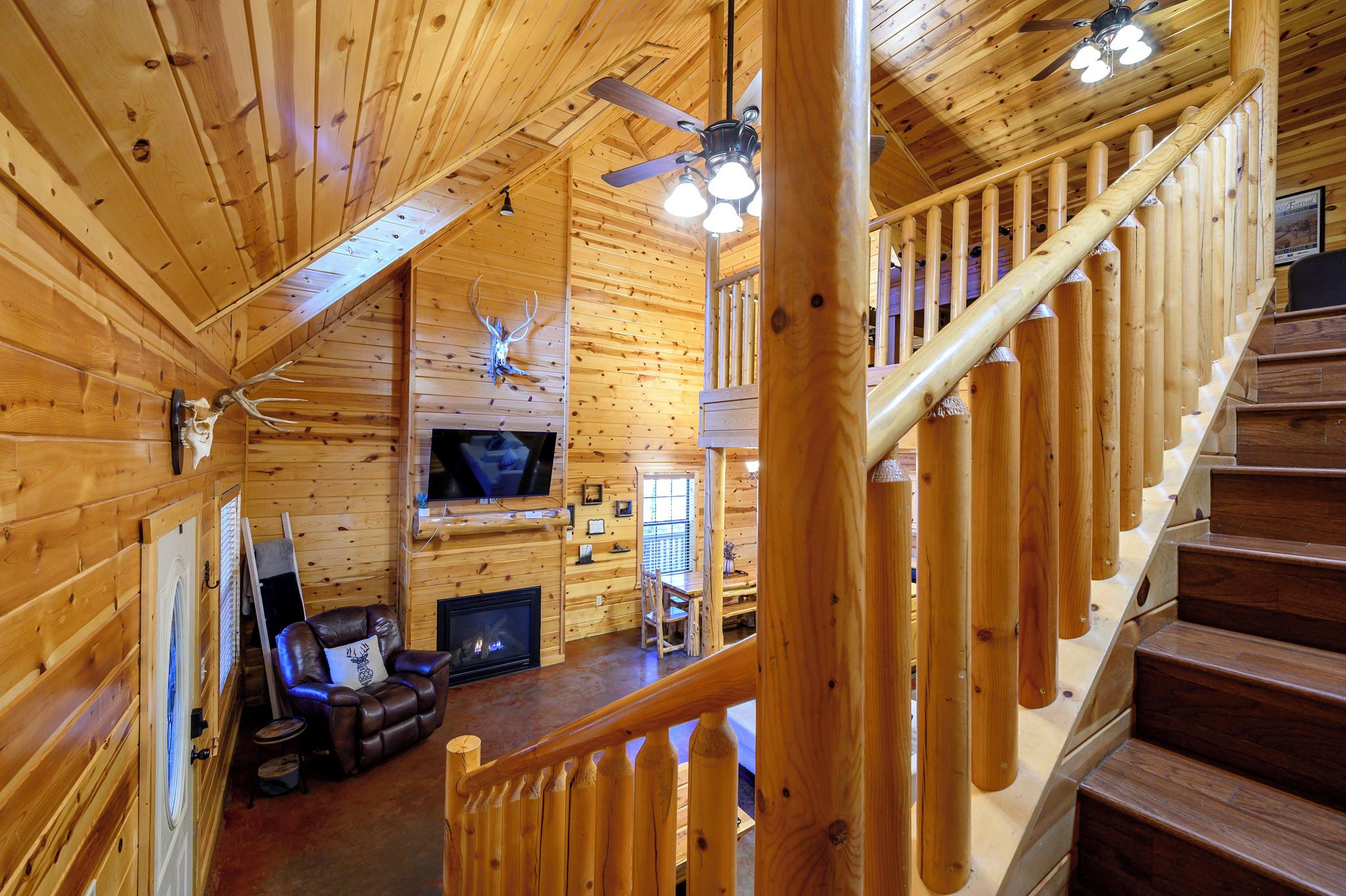 A wooden interior with a fireplace, leather chair, and a staircase.
