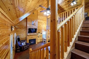 A wooden interior with a fireplace, leather chair, and a staircase.
