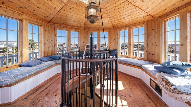 A wooden interior with a spiral staircase, large windows, and built-in seating areas.