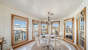 A dining room with a round table, white chairs, and a chandelier.