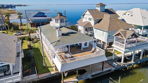 A coastal house with a large deck, a separate tower, and a view of the sea.