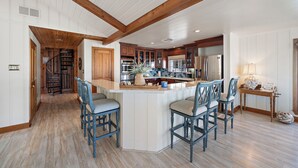 A spacious kitchen with wooden beams, a central island with bar stools, and modern appliances.