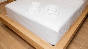 Una habitación de hotel moderna con estructura de cama de madera, ropa de cama blanca y una mesita de noche de madera.