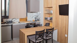 Una cocina compacta con una mesa de comedor de madera, dos sillas y un mueble empotrado para televisión.