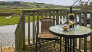 A deck with a wicker chair and a table, a bottle, and a bowl of nuts. - 2 bedroom accommodation in Rathmell, near Settle (Rathmell, near Settle)