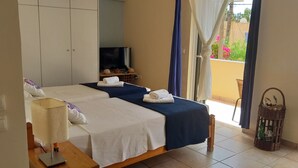 Ein Hotelzimmer mit zwei Betten, einem Fernseher, einem Schreibtisch und einem Korbwäscheschrank.