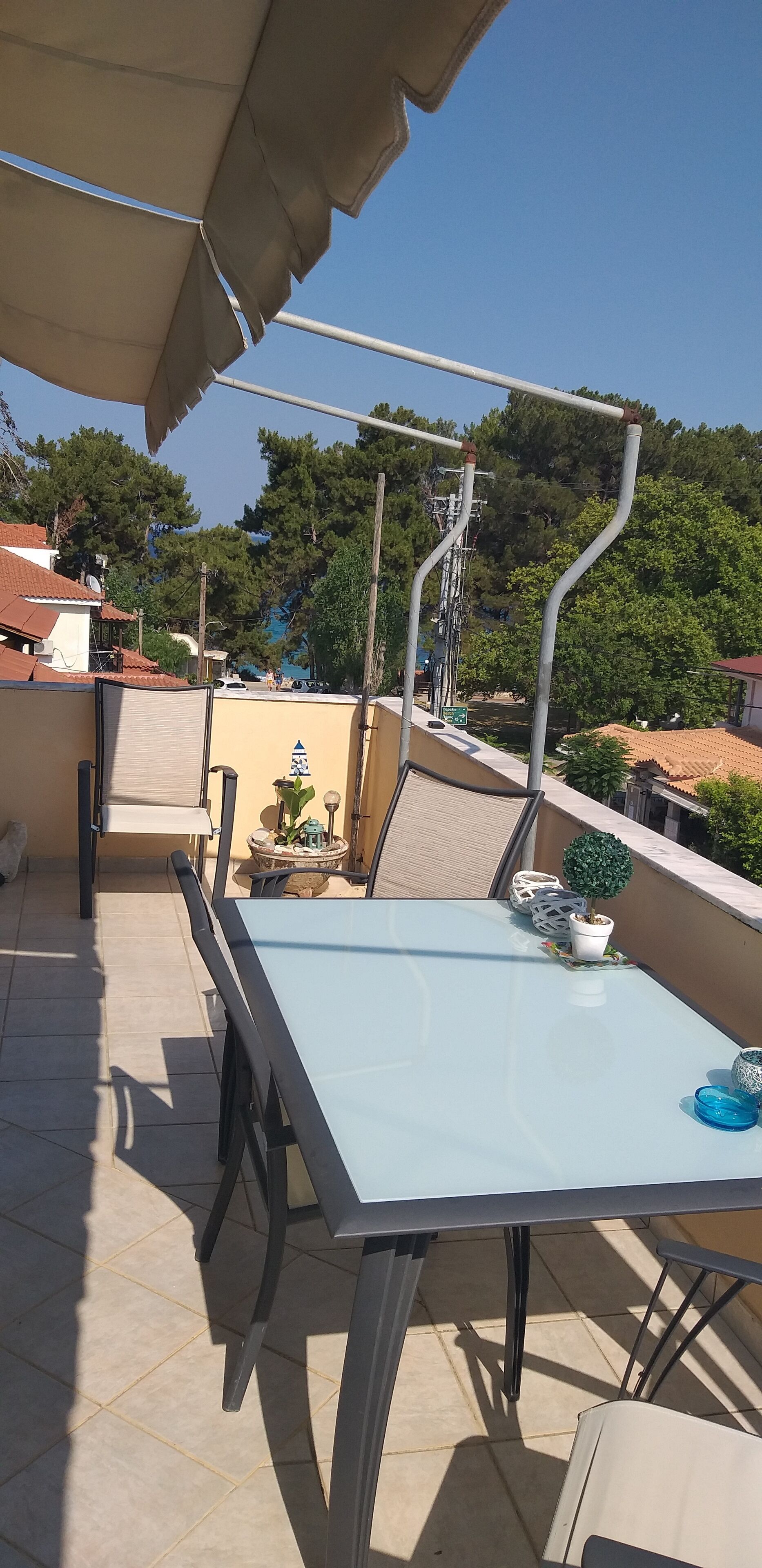 A rooftop terrace with a table and chairs, a small potted plant, and a view of the surrounding neighborhood.