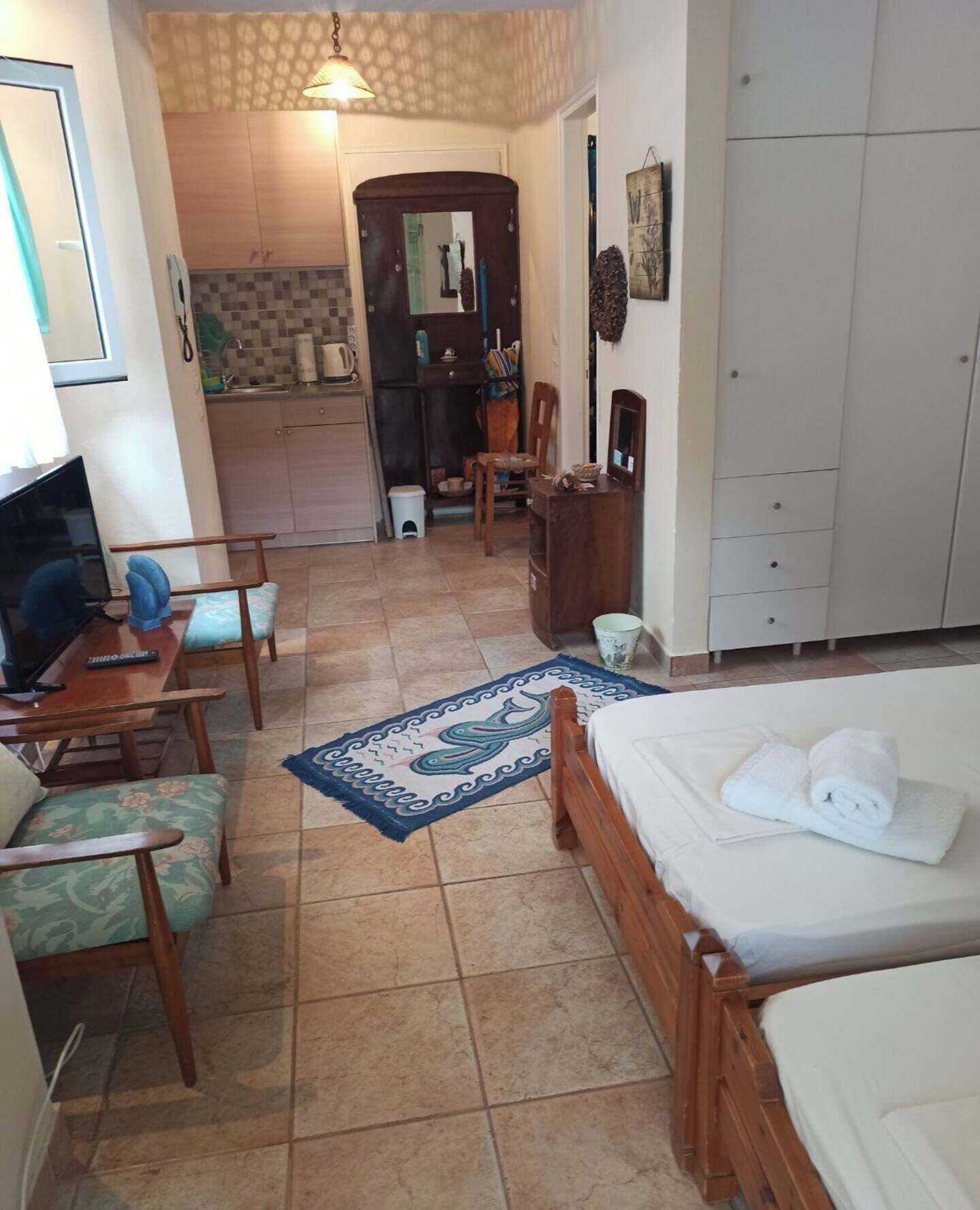 A hotel room with a bed, a desk, a chair, and a small kitchenette.