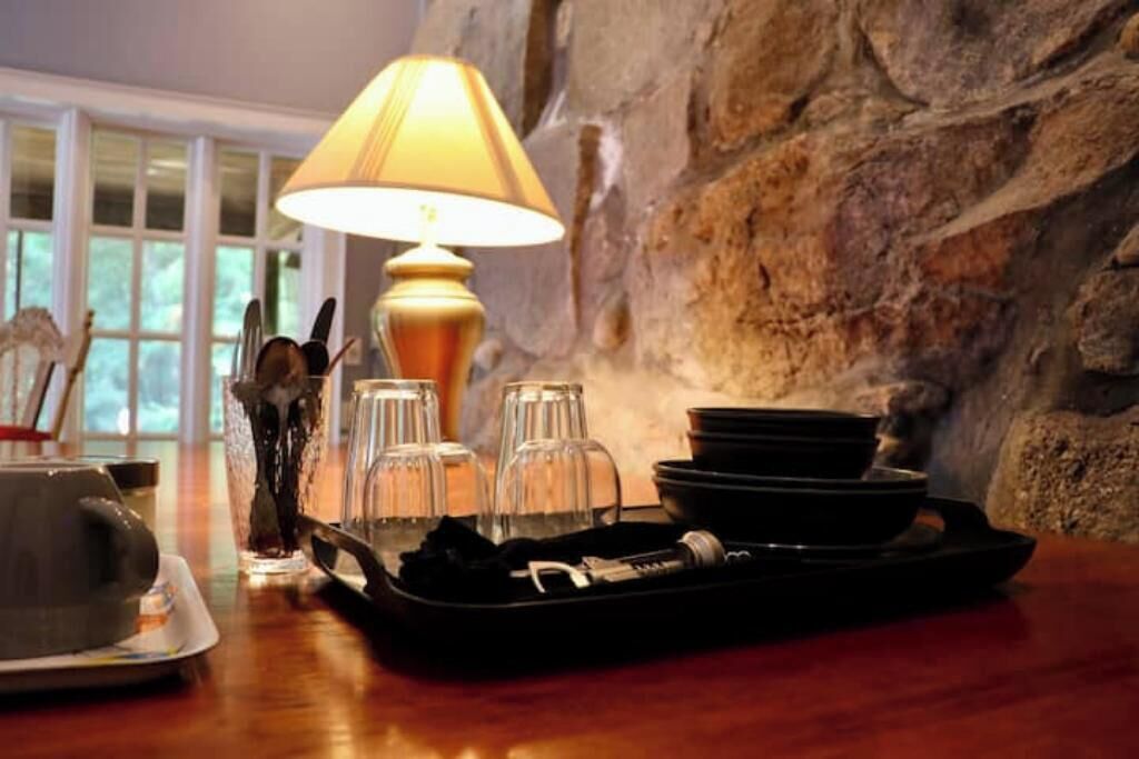 A dining table with a tray, plates, glasses, and a lamp.