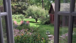 A conservatory with a view of a garden featuring various plants and flowers.