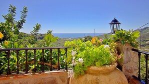 Ein Balkon mit Steinreling, Pflanzgefäßen und einer Laterne.