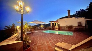 Ein Poolbereich auf dem Dach mit einer Pergola, Liegestühlen und einer Straßenlaterne.