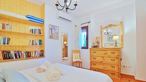 Ein Schlafzimmer mit einem großen Bett, einem Holzregal, einer Kommode und einem Spiegel.