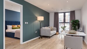 Een moderne hotelkamer met een bed, een bank, een eettafel en een groot raam.