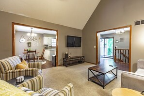 A spacious living room with a large sofa, a coffee table, and a dining area with chairs and a table. - Suburban Farmhouse w/ Match Soccer Vibes (Overland Park)