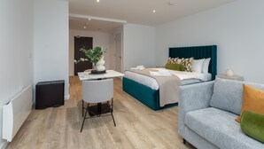 A modern hotel room with a bed, a sofa, a desk, and a chair. - Stylish City Studio (Manchester)
