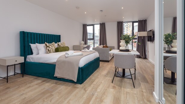 A modern hotel room with a large bed, a desk, and a chair. - Stylish City Studio (Manchester)