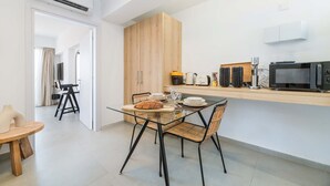 A modern kitchen with a glass dining table, wicker chairs, and wooden cabinets. - Finikoudes Marina View 202 - Charming Larnaca Centre Getaway (Larnaca)
