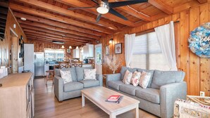 A spacious living area with two grey sofas, a wooden coffee table, and a ceiling fan. - Look and Sea: Dog-friendly Ocean View Cottage with Pool Table (Oak Island)