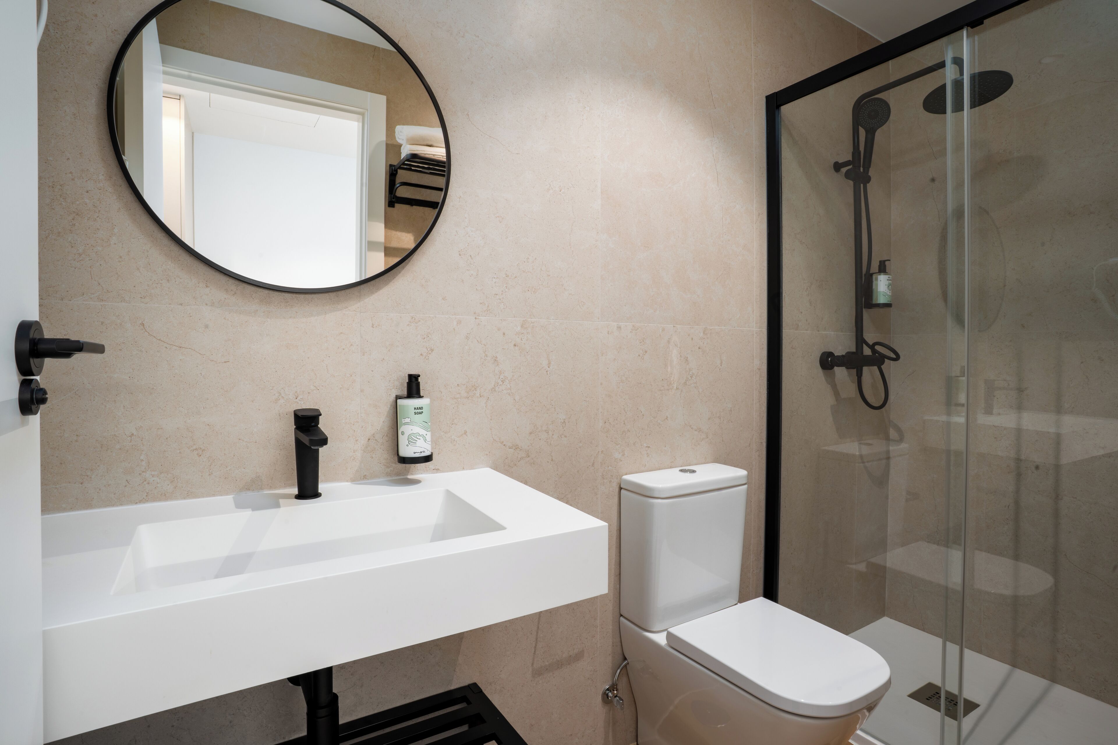 Une salle de bain moderne avec un lavabo blanc, des toilettes et une douche à parois de verre.