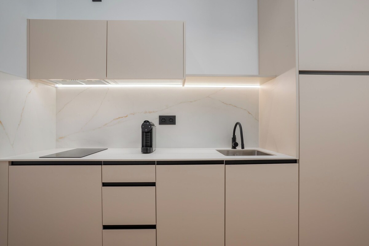 A modern kitchen with a marble countertop, a built-in coffee maker, and a sleek faucet.